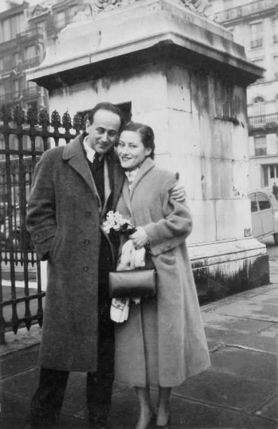 b/w photo, man with closed eyes holds woman in arm, both in long coats