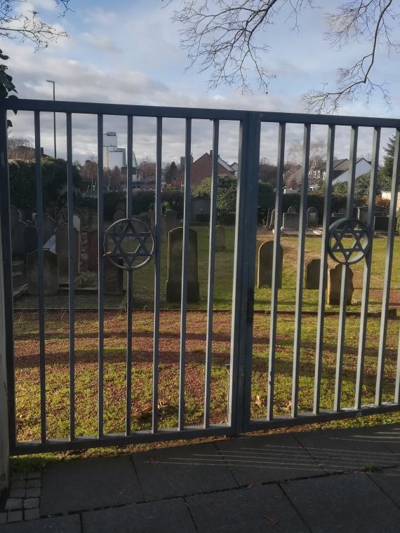 The cemetery area of approx. 400 square meters is bordered to the east and south sides by approx. 3.0 meter high, light gray brick walls facing the eastern Roman Road and the southern Mill Road. The access gate is located in the middle of the eastern wall.