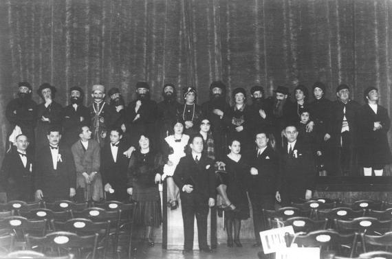 Many musicians and performers in front of a closed curtain