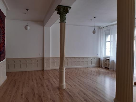 Interior of a room divided in two by slender iron columns, simple and stylishly decorated, wooden paneling on the walls