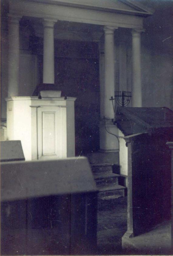 Black and white photograph of the interior of the synagogue with a view of a white Torah shrine.