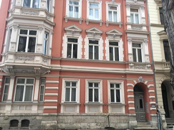 On the photzo shows a large multi-storey building with many window sections. At the bottom right is the entrance door, while around it are the many windows.