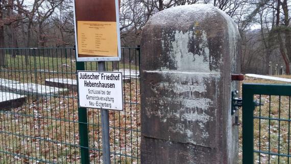 Cemetery entrance with stone inscription (no longer legible) and notice board of the municipality of Neu-Eichenberg that the key is to be collected from the administration.
