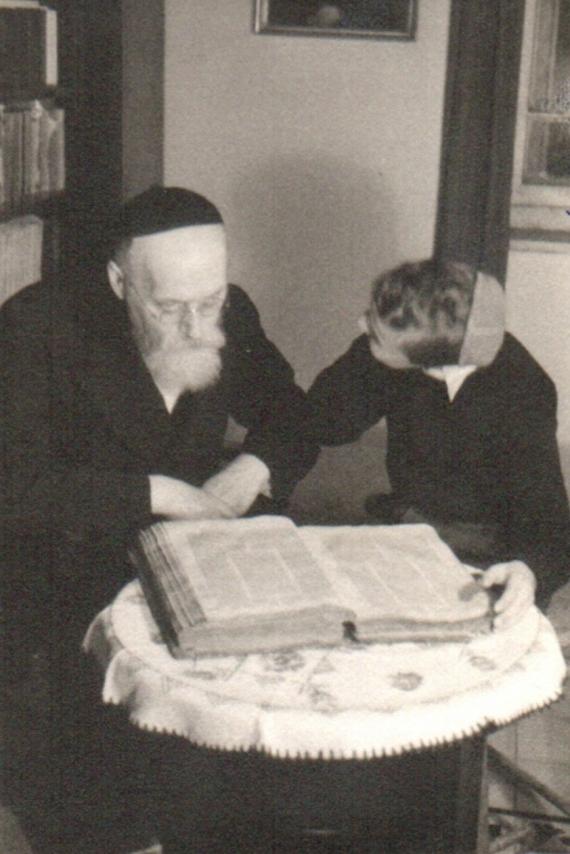 Schwarz-Weiß Foto zeigt Rabbiner Unna mit einem kleinem Jungen an einem aufgeschlagenem Buch 