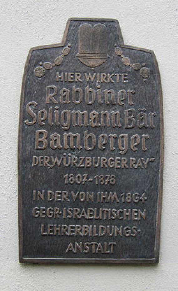 Gedenktafel mit rundlichen Kanten, oben flaschenhalsförmige Ausbuchtung
