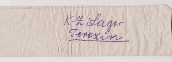 Armbinde von Clara Spaleck geb. Eisenkraft (Vorderseite) Man sieht eine Armbinde aus hellem Stoff mit dem handschriftlichen Schriftzug "K-Z Lager Terezin". Die Armbinde gehörte Clara Spaleck.