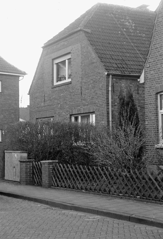 Simple two-storey house with hipped roof, directly on the street, small front garden.