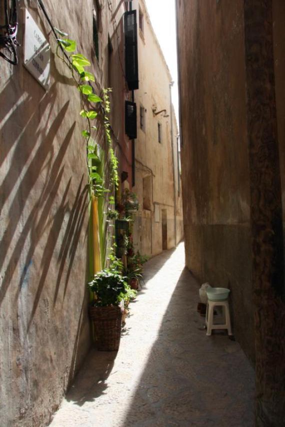 A narrow street with high walls of houses, old ghetto street