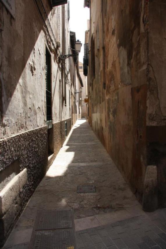 A narrow street with high walls of houses, old ghetto street