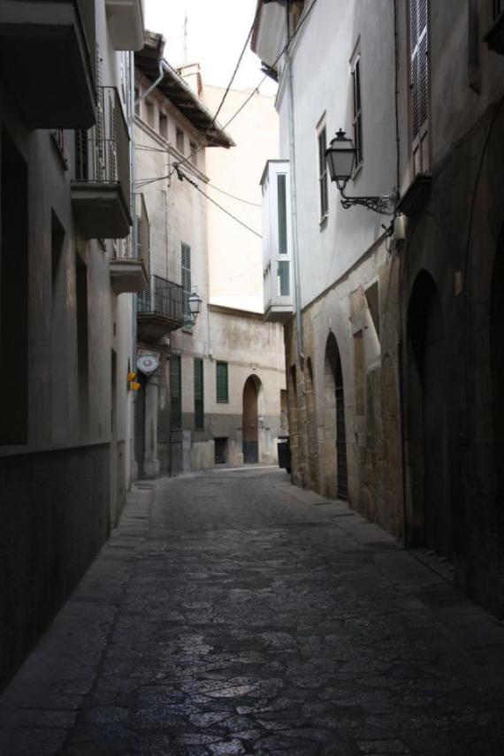 A narrow street with high walls of houses, old ghetto street