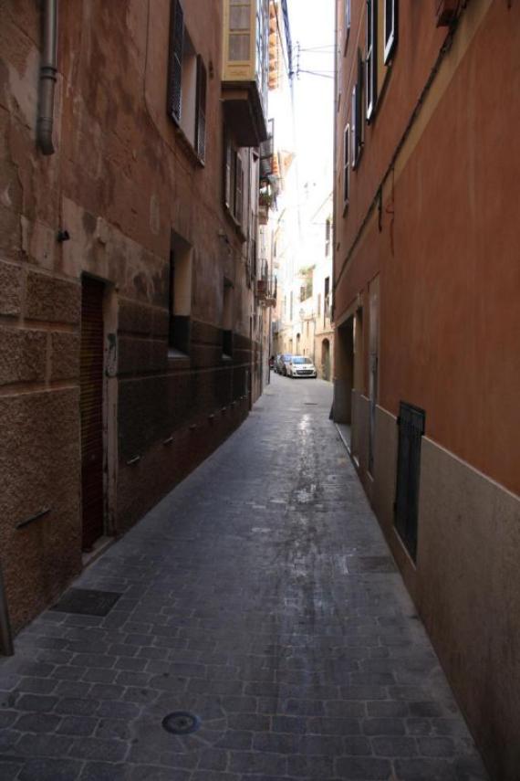 A narrow street with high house walls, dark, old ghetto street