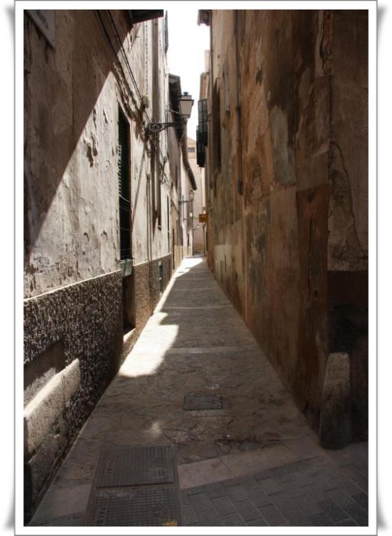 A narrow street with high house walls, dark, old ghetto street