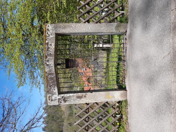 The simple gate consists of two stone columns with beams. The forged gate wings are each decorated with a Jewish star. A plaque, no longer legible at the bottom, is placed in the center. The rest of the cemetery is enclosed by a wooden hunter's fence.