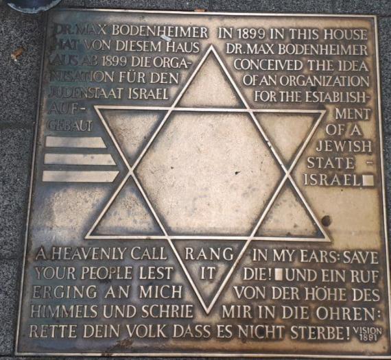 Memorial plaque in the floor with Star of David and inscription in German and English.
Inscription: "Dr. Max Bodenheimer built up the organization for the Jewish State of Israel from this house from 1899."


