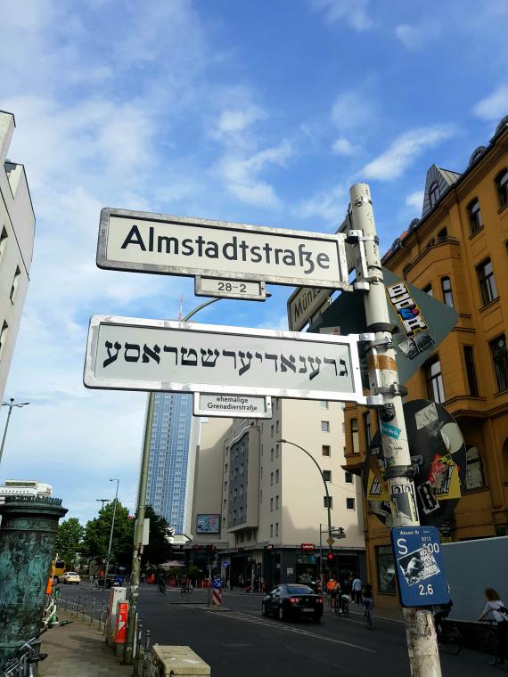 Ein Straßenschild auf Deutsch mit dem Namen Almstadtstraße, darunter ein Straßenschild auf Jiddisch mit dem Namen Grenadierstraße