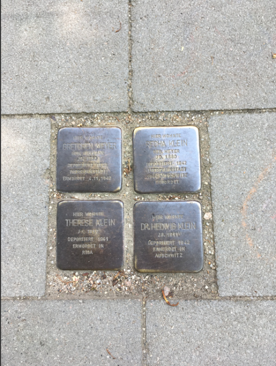 In einem Quadrat liegen vier Stolpersteine auf dem Boden als Erinnerung an die Mitglieder der Familie Klein: Gretchen Meyer, Recha Klein, Therese Klein, Dr. Hedwig Klein. 