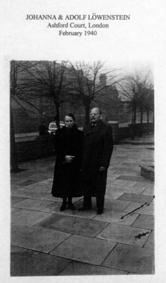 Black and white photograph of Trude Schiff's parents in winter clothes standing on a street, in the background unleafed trees