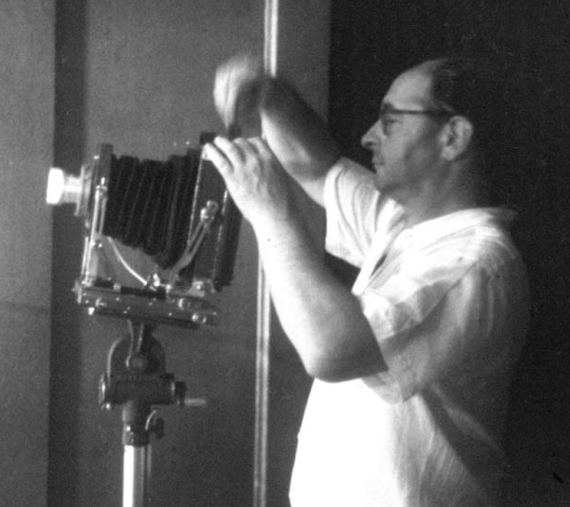 Black and white photograph of Hans Schiff (half-total) from profile, making concentrated settings on his camera