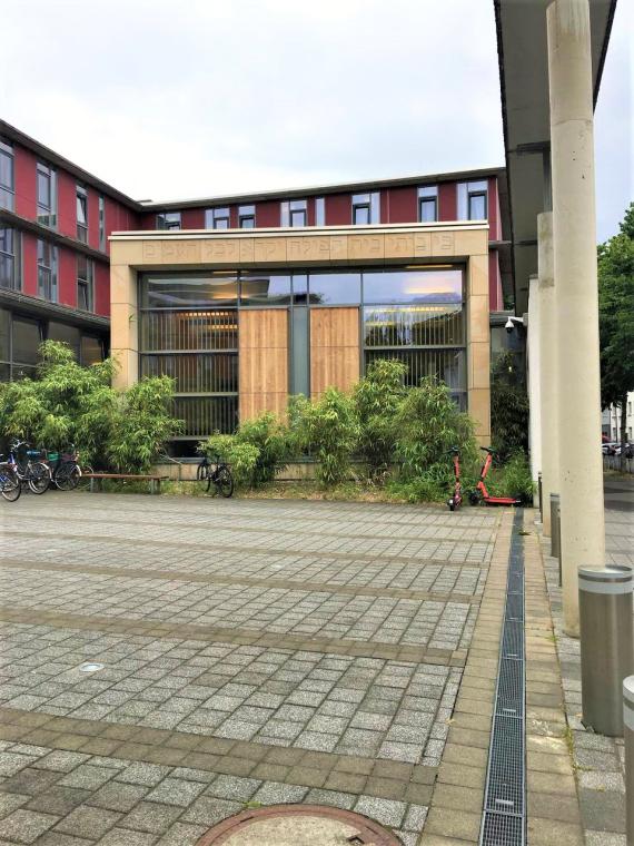 Außenansicht des Jüdischen Wohlfahrtszentrums Partial shot of the exterior with a large facade of glass. Above in the stone can be seen a Hebrew inscription.