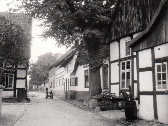 Langstrecktes Gebäude auf der rechten Straßenseite hinter den Kindern