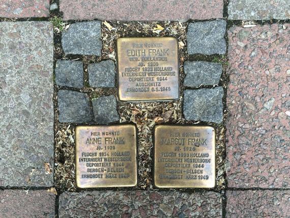 Three golden pavers installed in a sidewalk with normal pavers.
