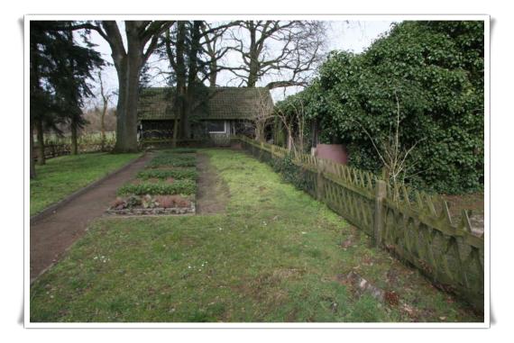 Some graves without gravestones. Lawn, a fence.