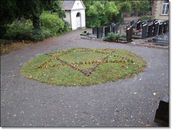 Magen David, der Davidstern, auf einer Grasfläche. Zwischen Wegen gelegen, Seitlich Wege.