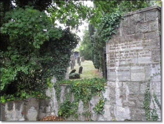 rechts ein Mahnmal an die Toten des 1. Weltkrieges, im Hintergrund Grabsteine