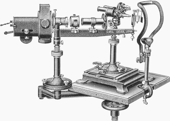 Complete slit lamp unit with a carbon arc lamp for examinations in light free of red color, on height-adjustable examination table. On the left is a swiveling and height-adjustable stand (actual arc lamp) and the so-called Hangman armfor the aplanatic aspherical illumination lens. A mirror device for cooling cuvette and for the so-called diaphragm tube (right) with 2 recoss disks for a quick filter change. In the center is the corneal microscope according to Czapski with revolving nosepiece u