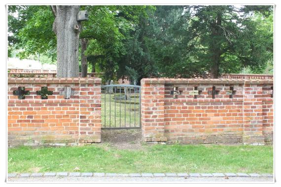 Brick wall, half high. Small recessed iron gate.