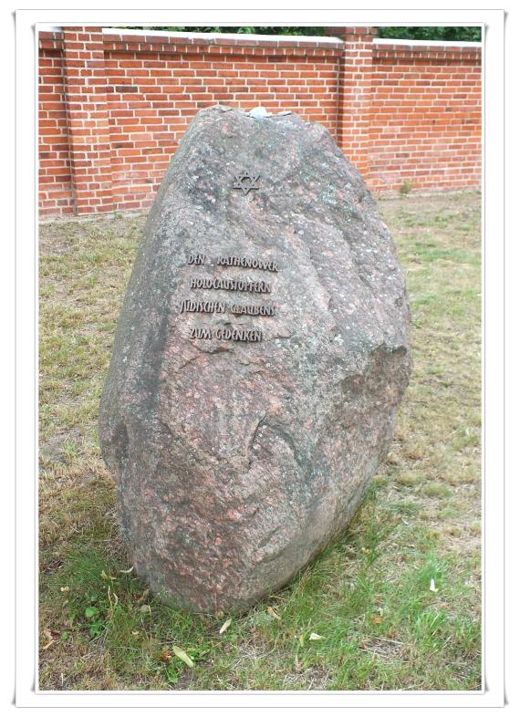 Ein hüfthoher Stein, verjüngt sich nach oben. Schrift aus metallenen Lettern. Zum Gedenken an die Rathenower Opfer des Holocaust.
