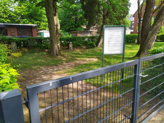 Gartenähnlicher und umzäunten Friedhof mit einzelnen Grabsteinen.