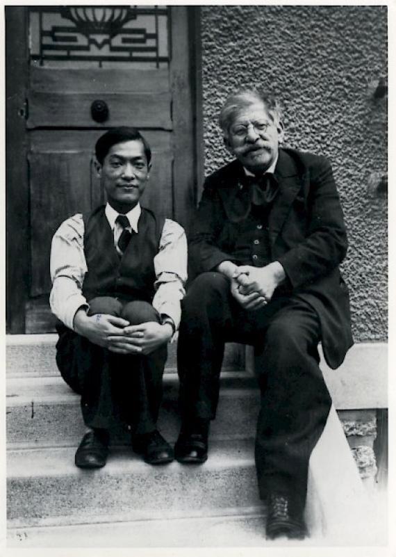 black and white shot, Hirschfeld sits next to doctor and companion, looking into camera