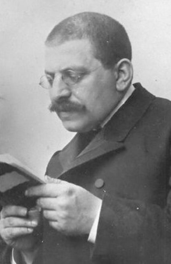 schwarz-weiß Aufnahme, seitliches Porträt von Magnus Hirschfeld, er liest in einem Buch