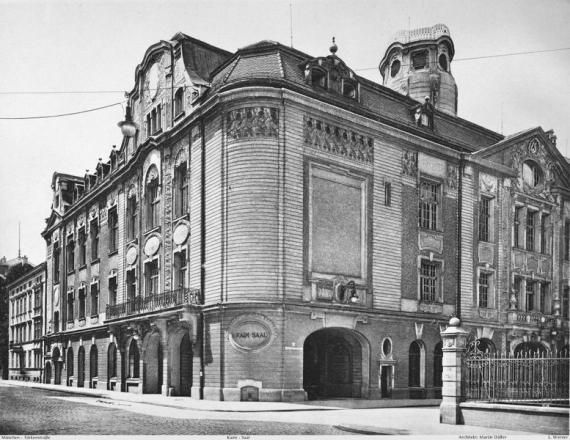 black and white shot of imposing corner building with gables and large ornate windows, photographed from the street