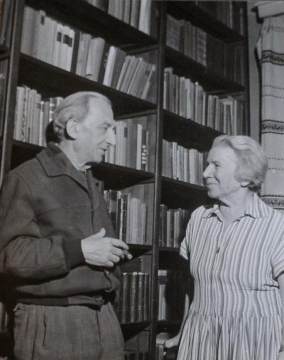 Black and white picture, elderly man and woman looking at each other in front of bookshelf