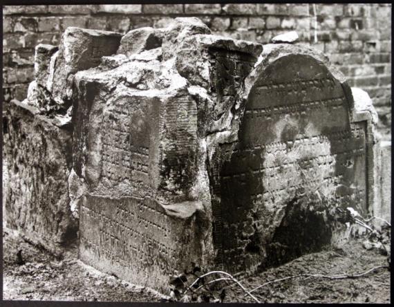 Numerous gravestones stacked together in front of a wall