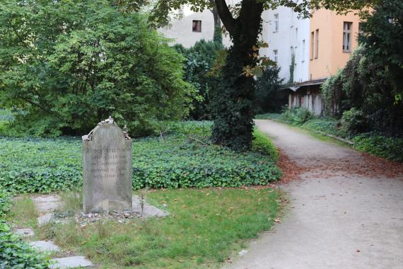 Links: Grasstück mit Grabstein, rechts: Wegstück