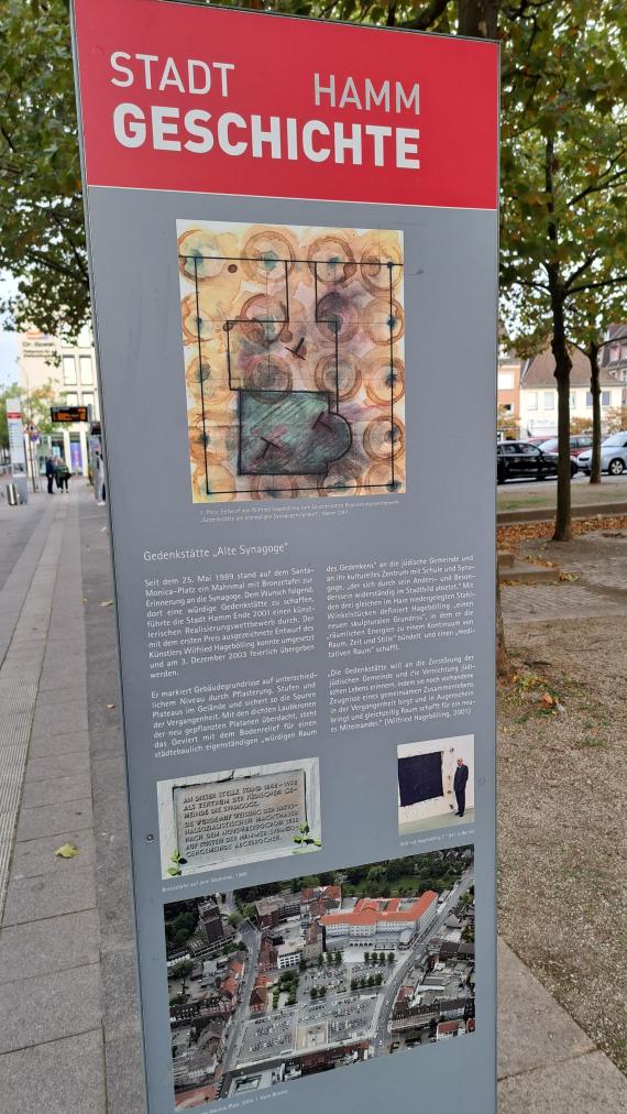Auf dem Bild ist eine Informationstafel mit Bildern und Text zu der Gedenkstätte "Alte Synagoge" zu sehen.