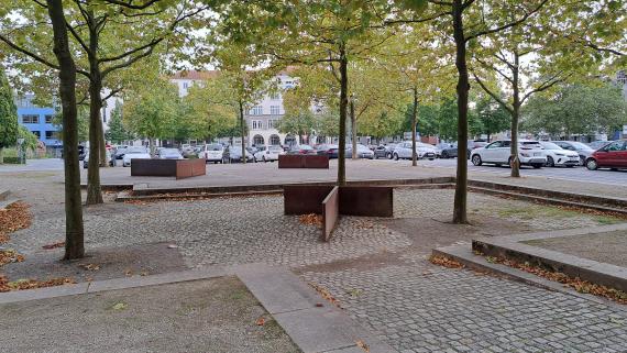 Auf dem Bild ist der ehemalige Standort der Synagoge zu sehen. Der Umriss der ehemaligen Synagoge wird durch Stufen und Plateaus sichtbar.