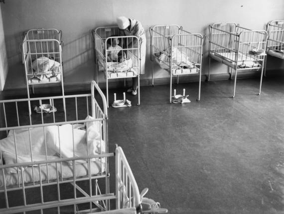 Cots in a row, nurse with a child