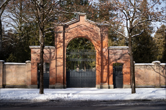 Large red brick gate. Sidewalk with snow in front of it. And the road in front of it.