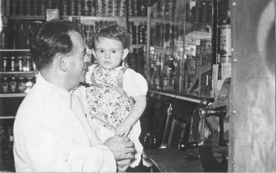 A man, smiling in a friendly manner, with a small child in his arms