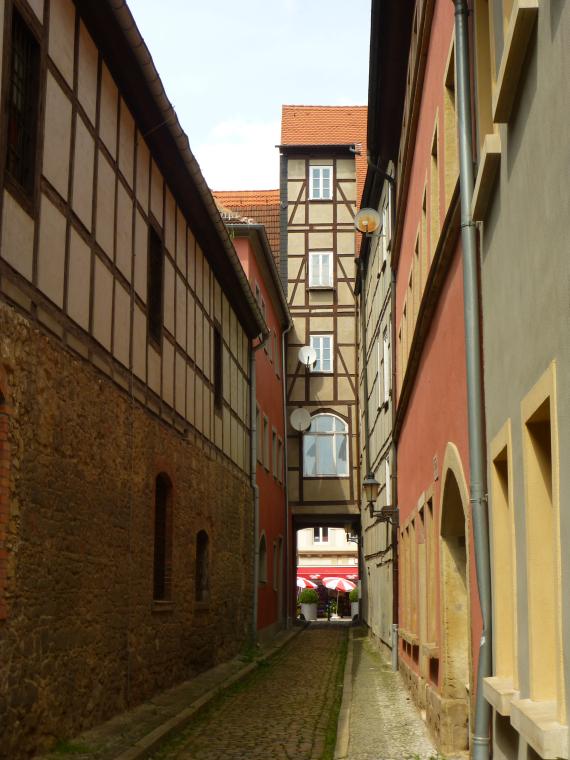 A five-storey half-timbered house with an archway and neighboring houses from different eras with different building heights.