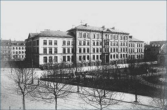 Street with trees in the foreground and large building complex in the background