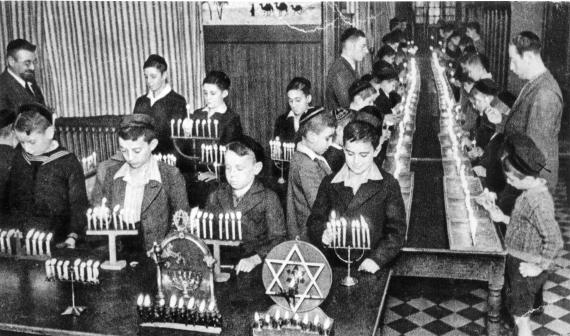 Children light Hanukkah candles in the dining room (?) of the orphanage