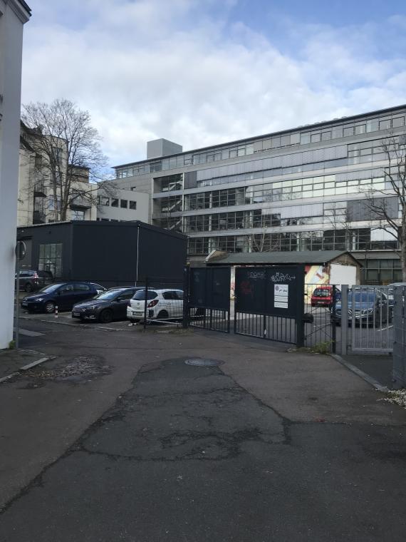 Fußgängerweg mit angrenzenden Büro- und Wohnhäusern, private Parkplätze, die über ein Tor zugänglich sind