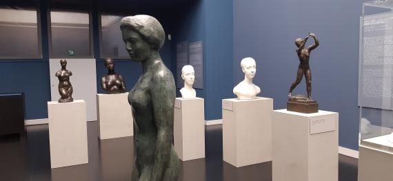 View into an exhibition room with several figures on pedestals distributed around the room