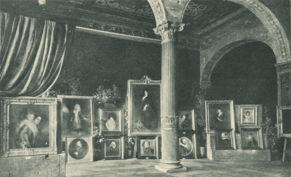 Richly decorated interior with a column in the middle, numerous paintings on pedestals on one wall