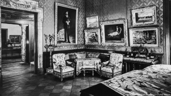 Black and white photograph of the interior of a historic villa with seating area and works of art